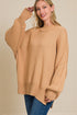 Woman wearing a beige sweater with a plain background