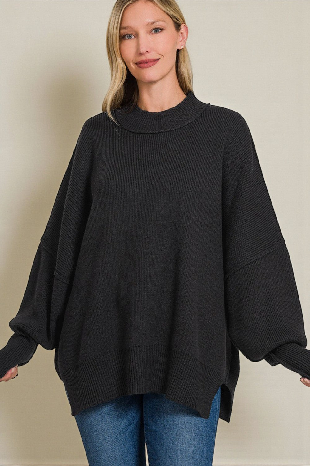 Woman wearing a black poncho over a plain background