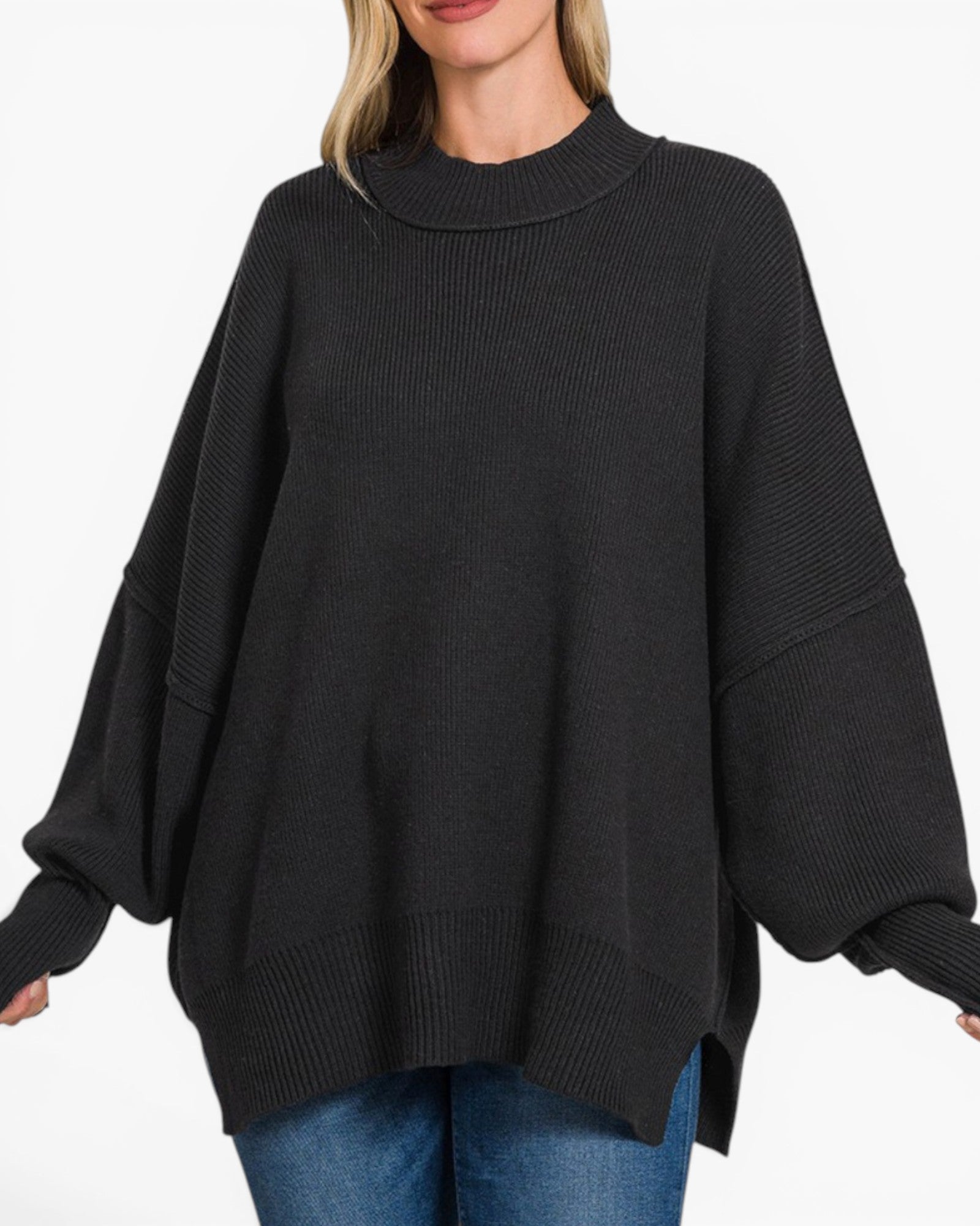 A woman wearing a black ribbed knit sweater with balloon sleeves and a mock neck, paired with blue jeans, against a plain white background.