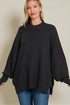 Woman wearing a black poncho over a plain background
