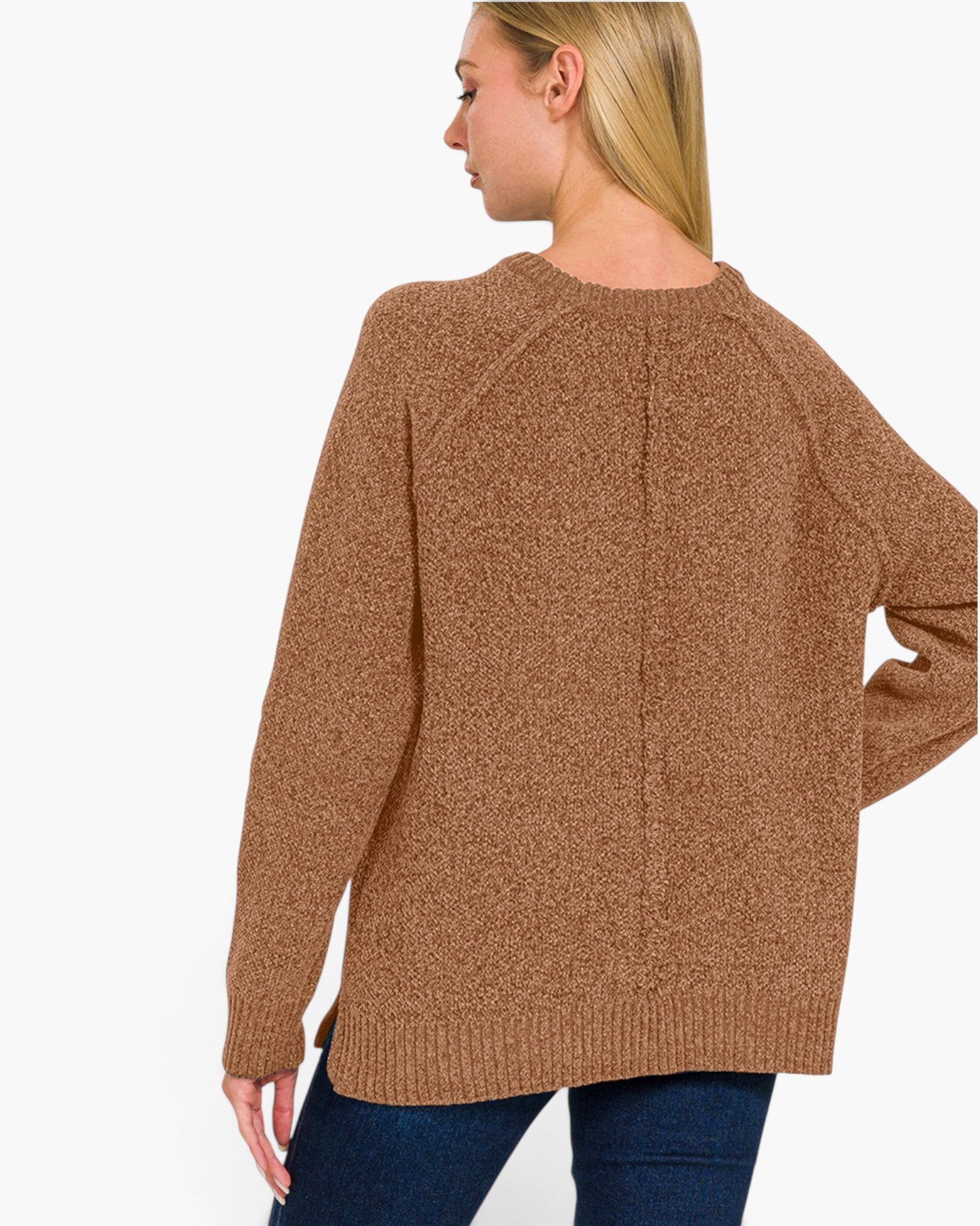 A woman shown from the back wearing a textured brown knit sweater and dark blue jeans against a plain white background.