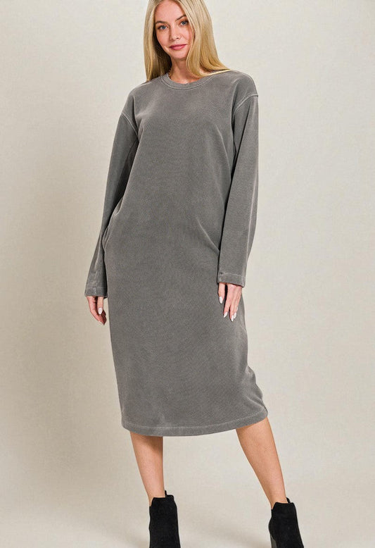 Woman wearing a gray dress with long sleeves on a plain background