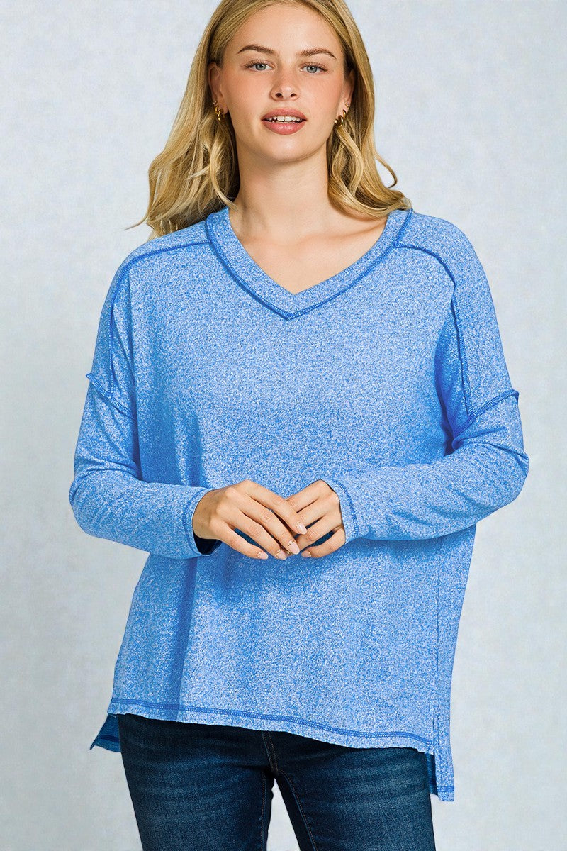 Woman wearing a blue long-sleeve top against a light gray background