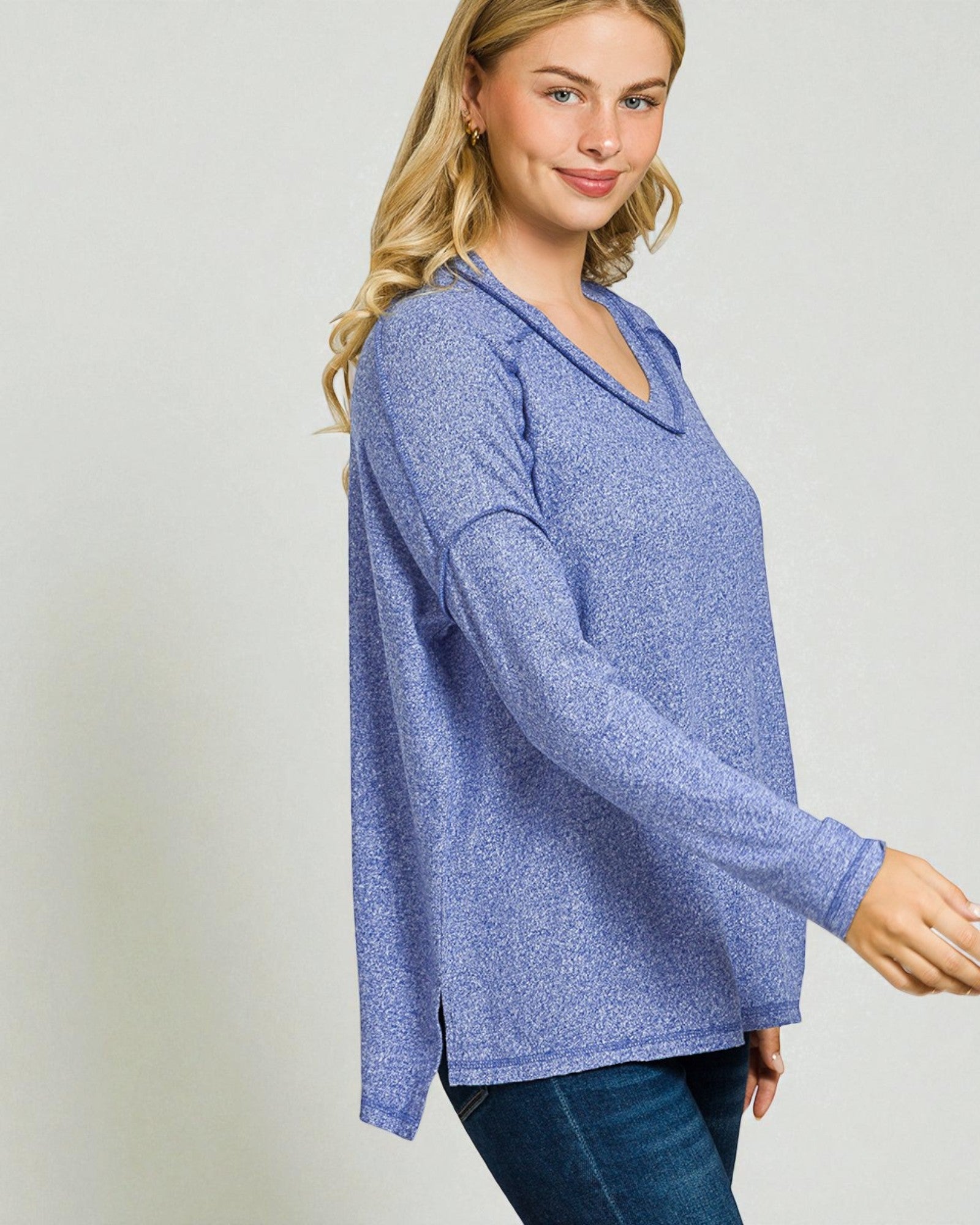 Woman wearing a blue long-sleeve top against a plain background