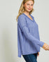 Woman wearing a blue long-sleeve top against a plain background