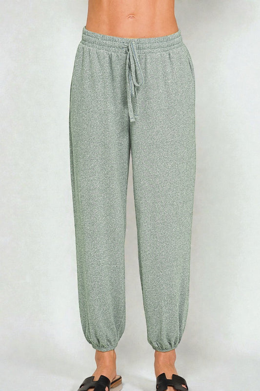 Green jogger pants worn by a person on a white background