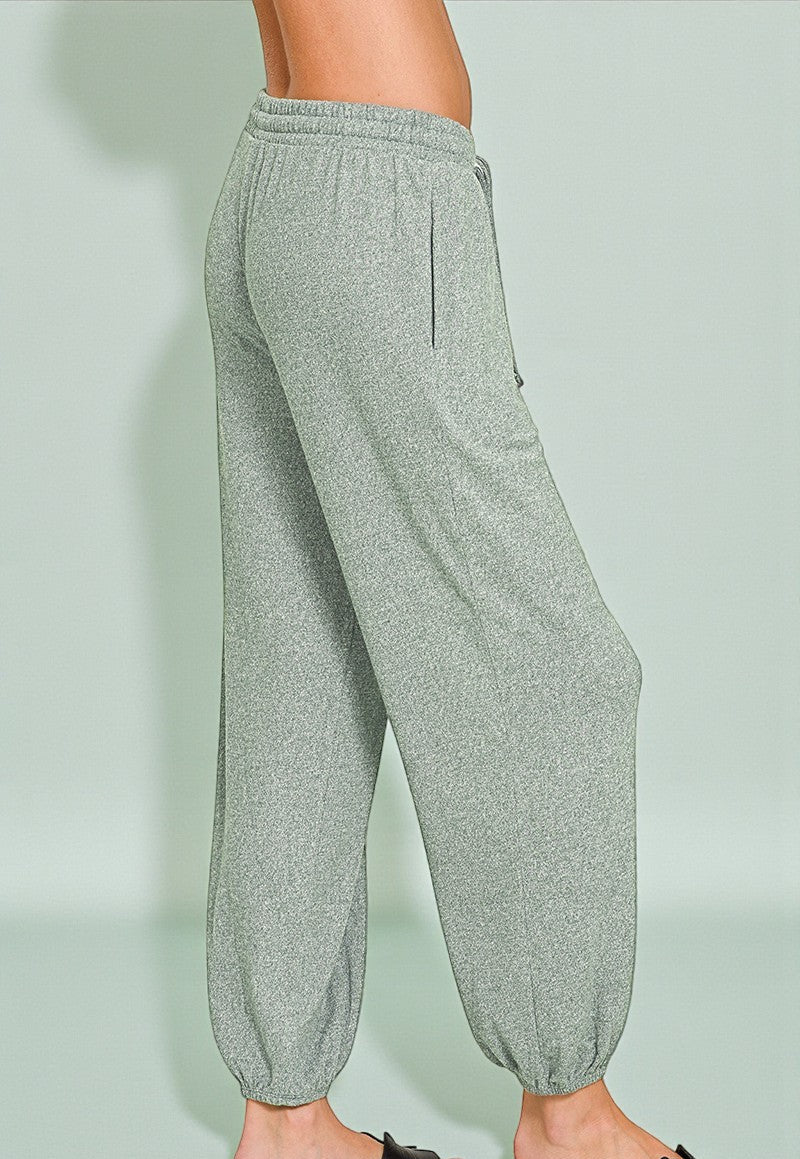 Gray jogger pants worn by a person on a light green background