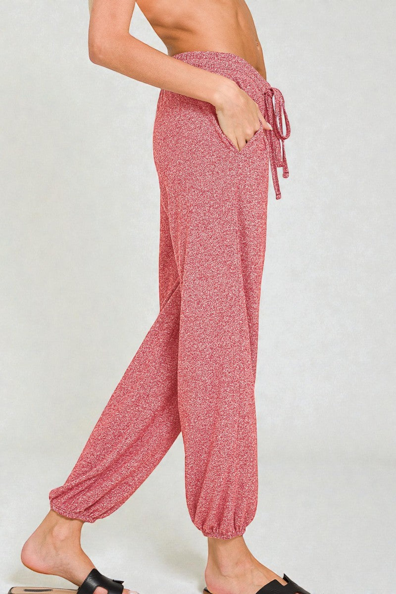 Pink drawstring pants worn by a person on a white background