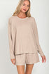 Woman wearing a beige long-sleeve top and shorts set on a white background