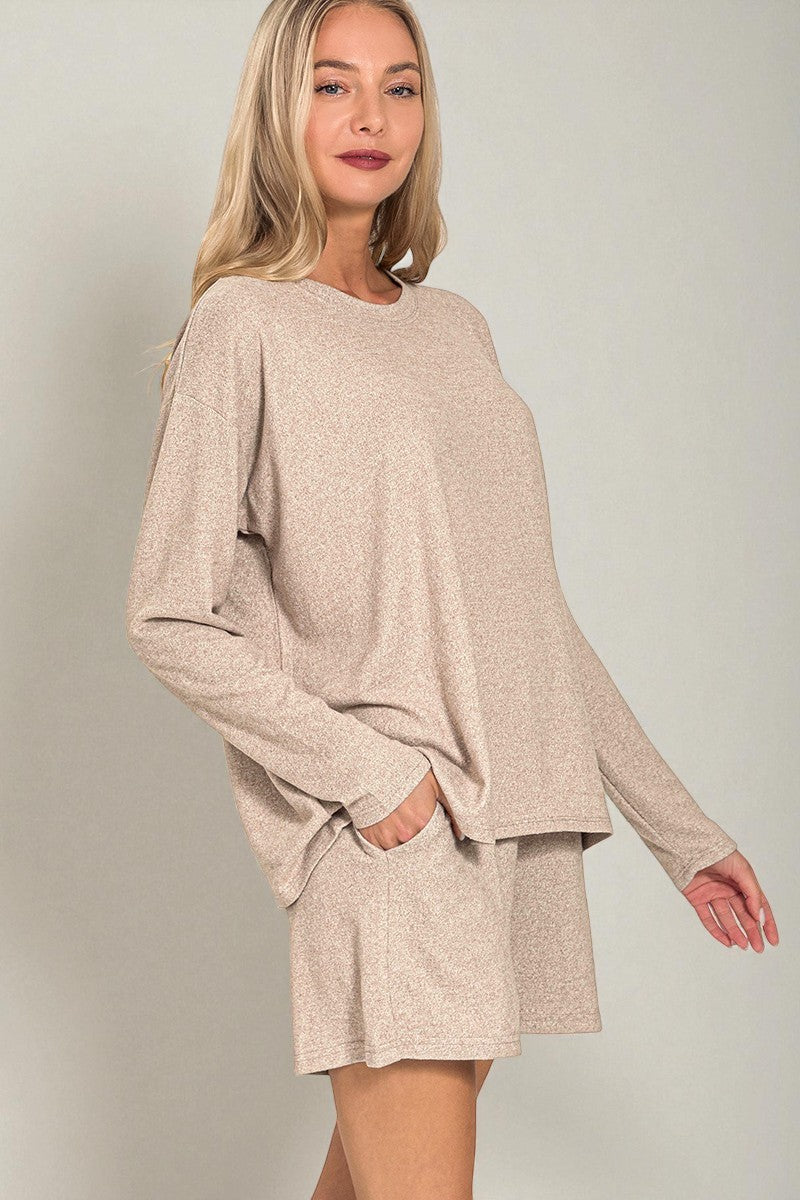 Woman wearing a beige long-sleeve top and shorts set against a plain background