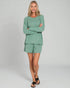Woman wearing a green outfit on a gray background