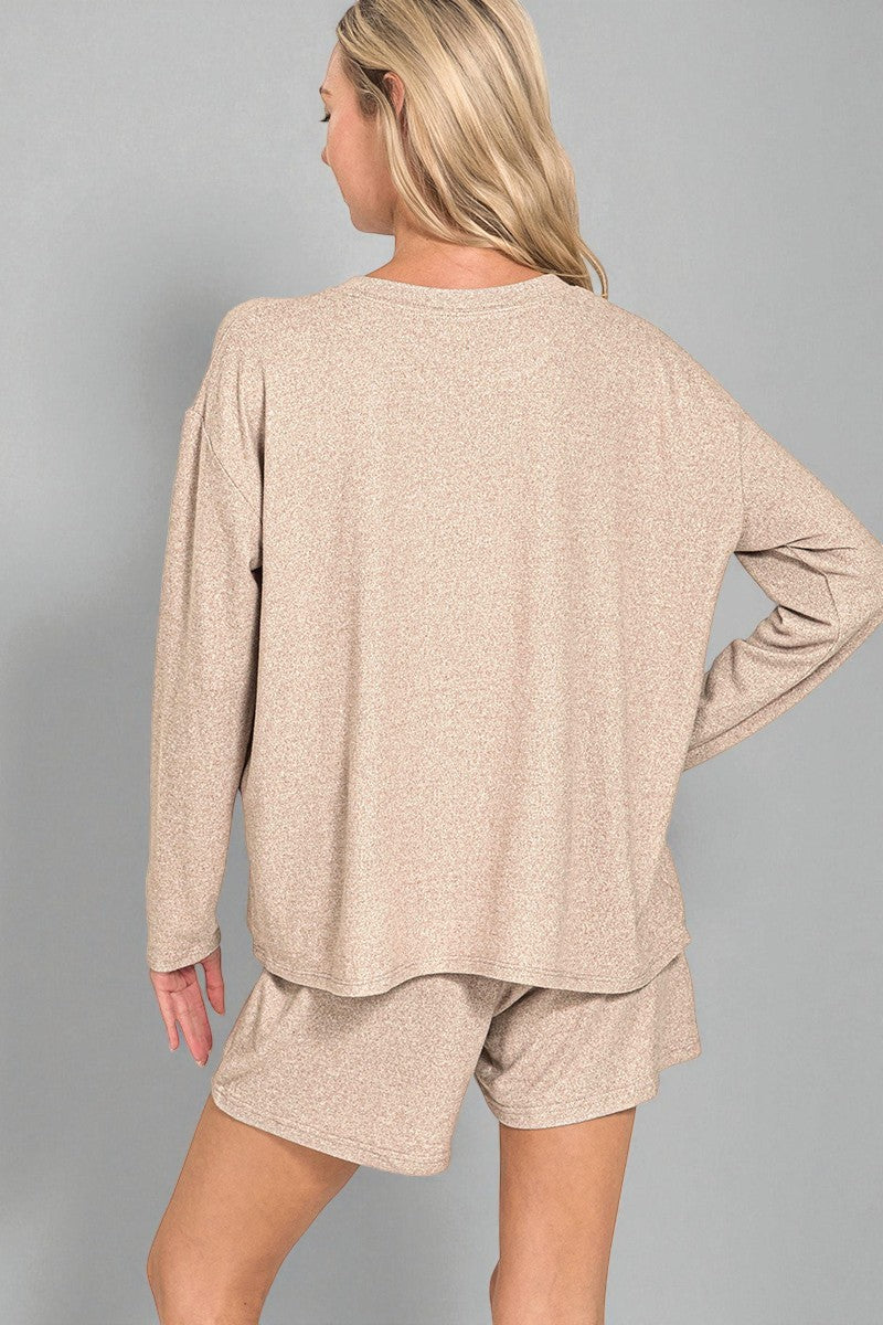 Woman wearing a beige long-sleeve top and shorts set on a gray background