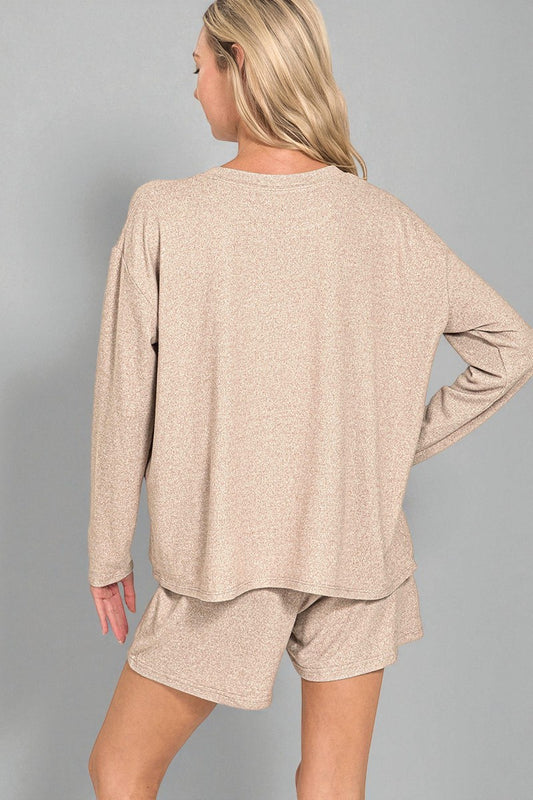 Woman wearing a beige long-sleeve top and shorts set on a gray background