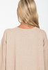 Beige sweater worn by a person with blonde hair on a white background