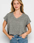 Woman wearing a gray patterned top and blue jeans on a white background