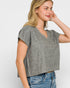 Woman wearing a gray marled top and blue jeans on a white background