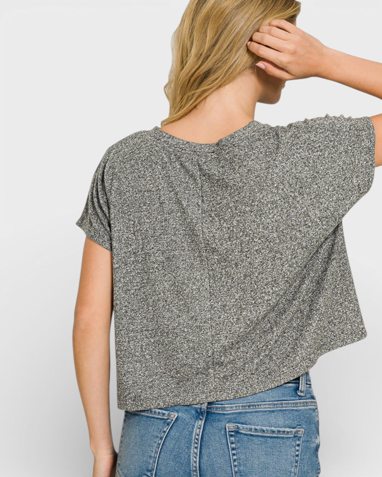 Person wearing a loose-fitting gray t-shirt and blue jeans on a plain background