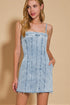 Woman wearing a light blue denim dress against a beige background