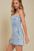 Woman wearing a light blue denim dress against a beige background