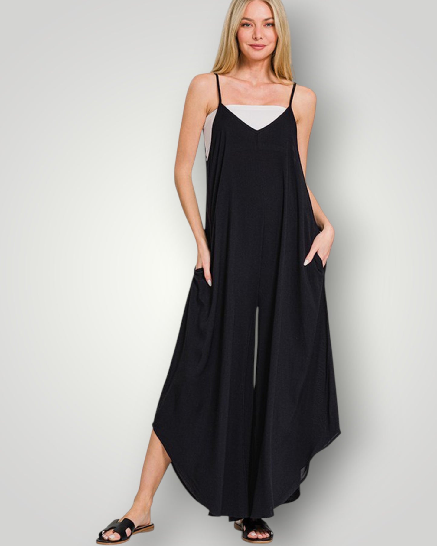 Woman wearing a black slip dress with a white top on a gray background