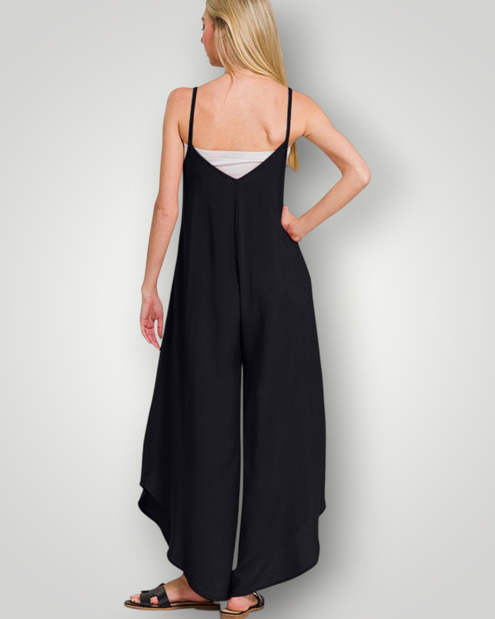 Woman wearing a black slip dress on a plain background