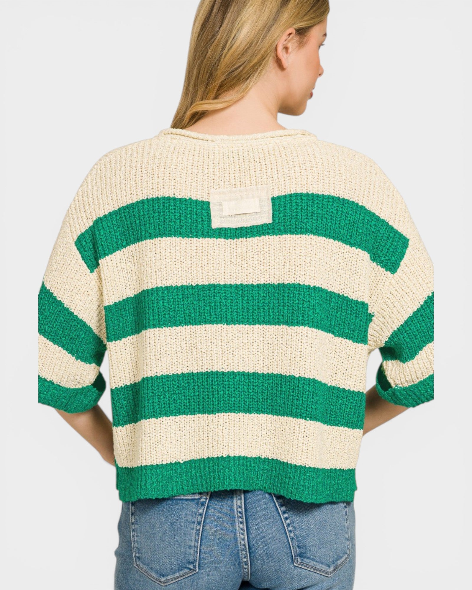 Person wearing a green and beige striped sweater on a plain background