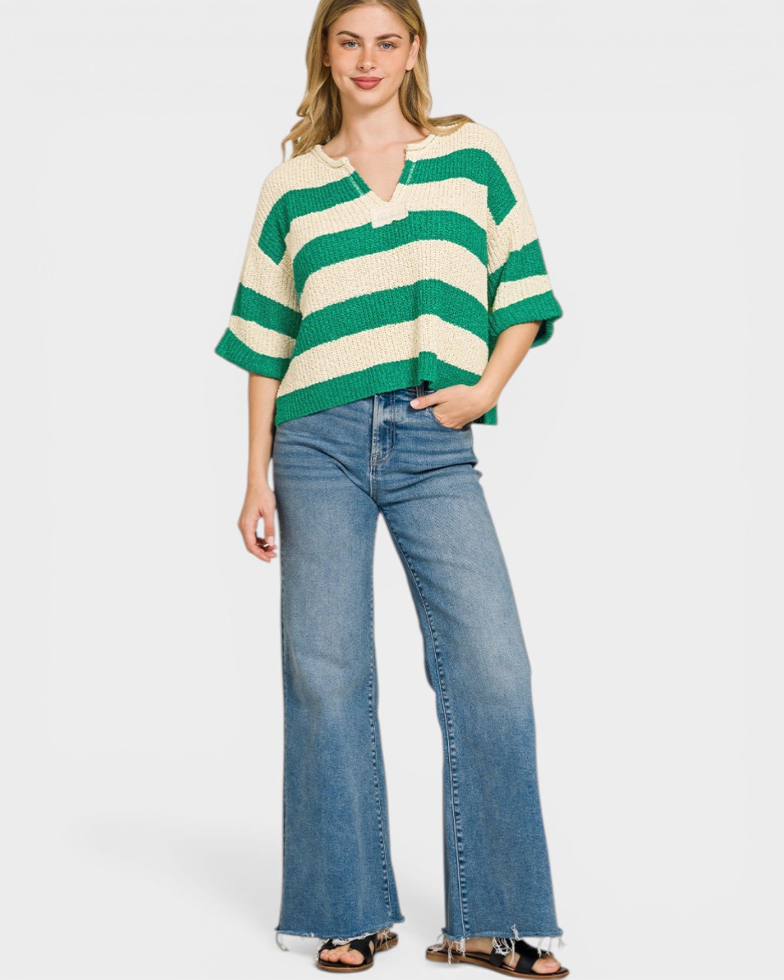 Woman wearing a green and white striped sweater and blue jeans on a white background