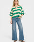 Woman wearing a green and white striped sweater and blue jeans on a white background