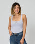 Woman wearing a gray tank top and blue jeans against a plain background