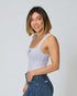Woman wearing a light gray tank top and blue jeans against a plain background