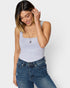 Woman wearing a light gray tank top and blue jeans against a white background