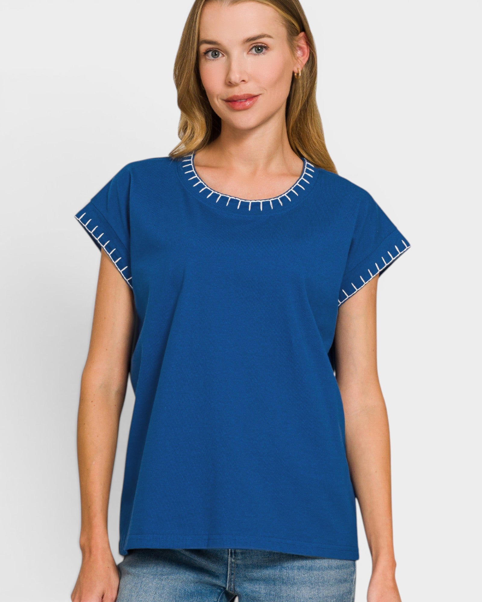 Woman wearing a blue top with white trim on a plain background