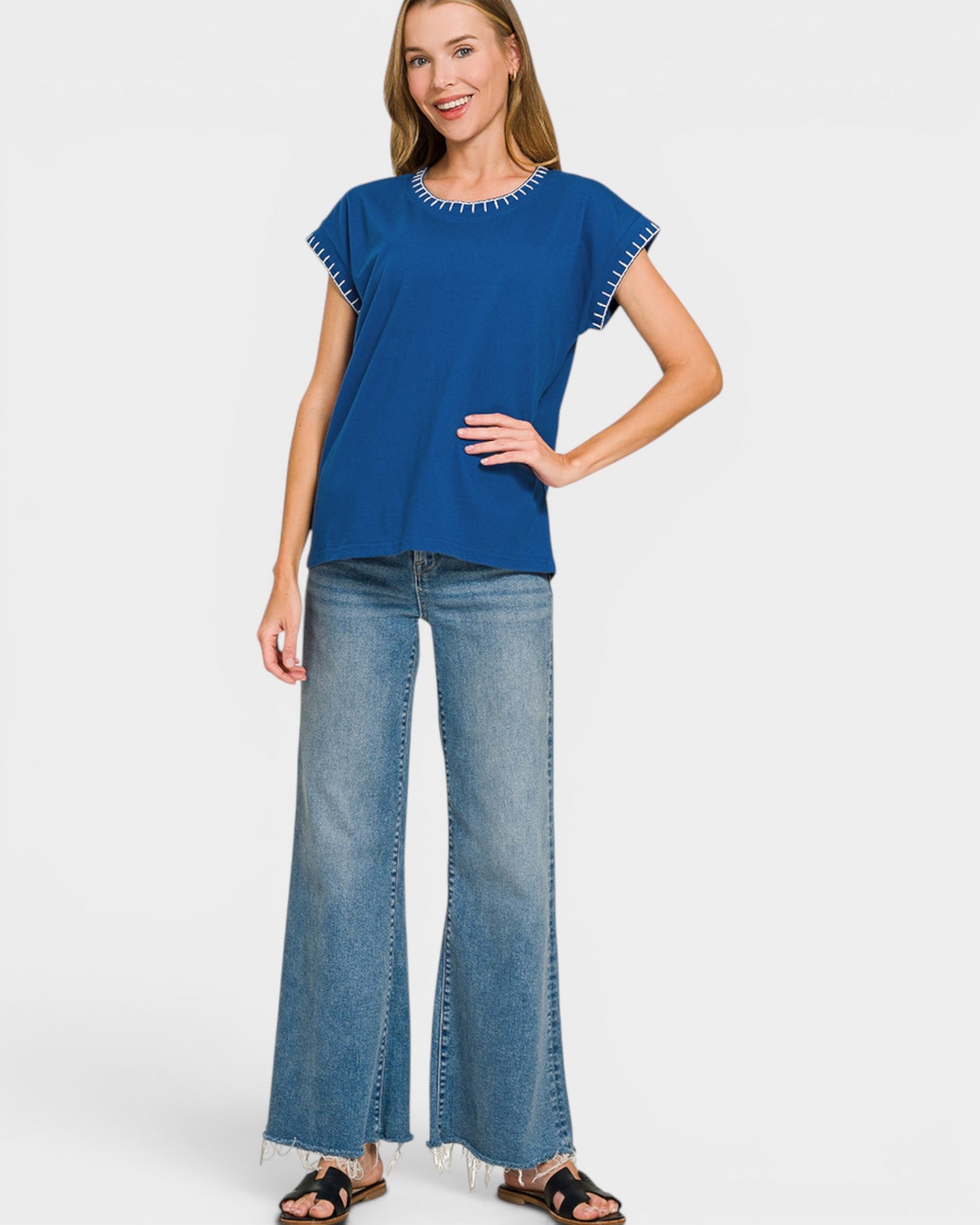 Woman wearing a blue top and light blue jeans on a white background