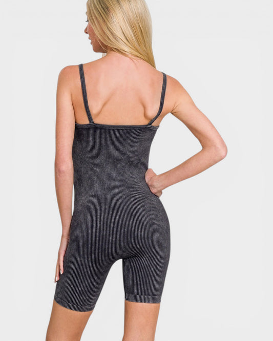 Woman wearing a black denim-style romper on a plain background