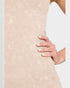 Beige ribbed dress with a hand touching the fabric on a light gray background