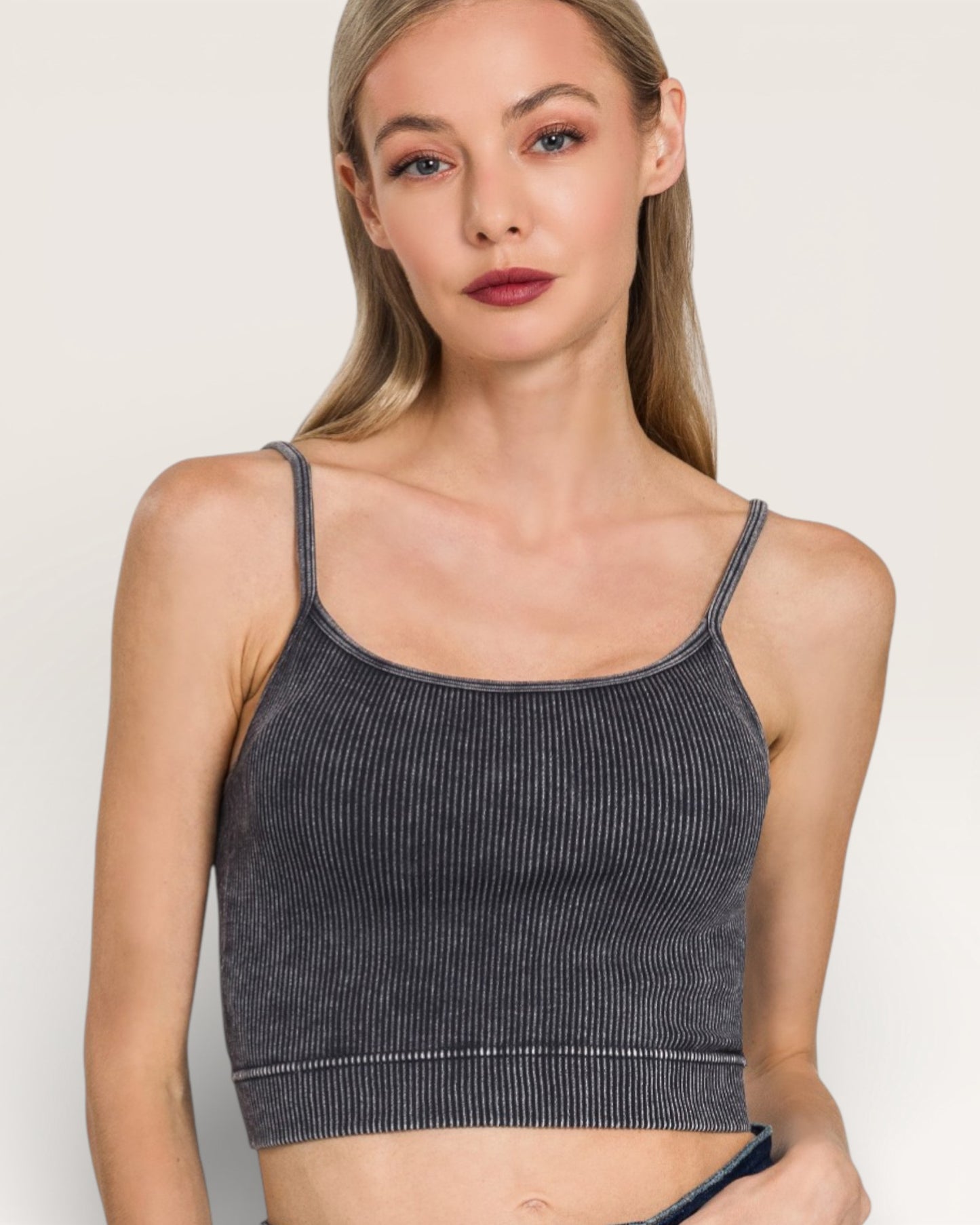 Woman wearing a dark gray ribbed tank top against a plain background