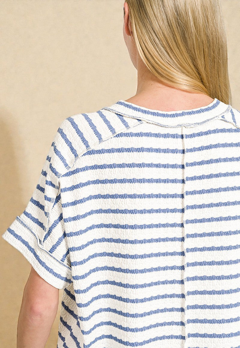 Person wearing a blue and white striped shirt against a beige background