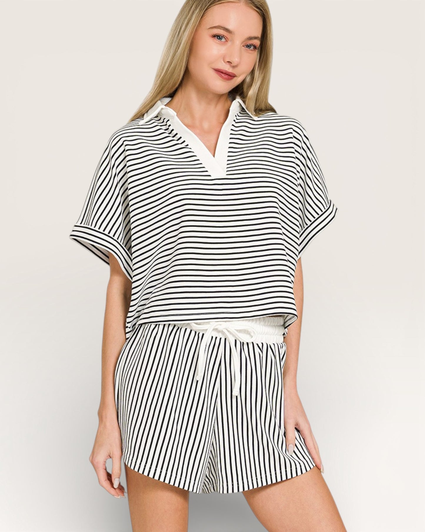 Woman wearing a black and white striped outfit on a plain background