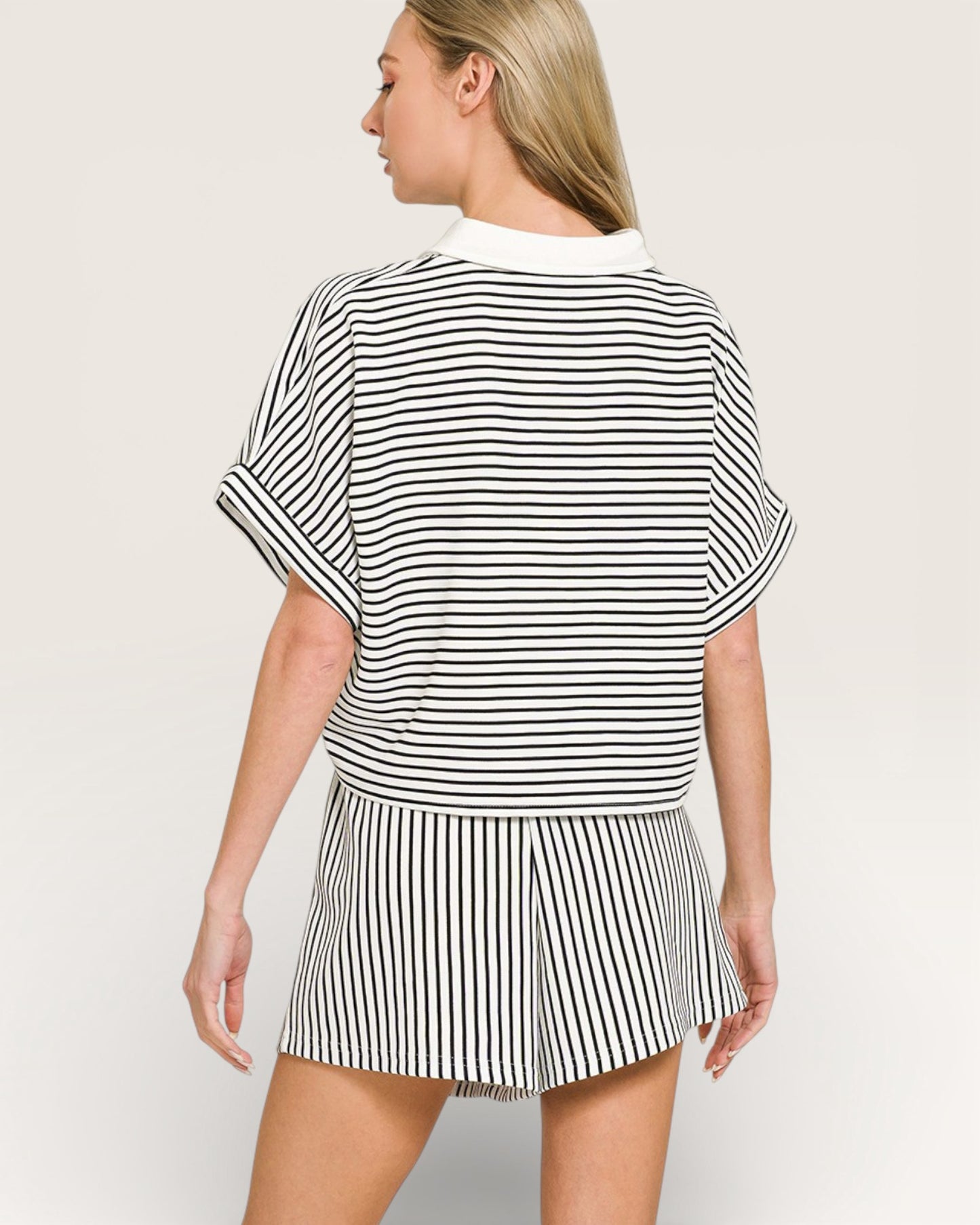 Woman wearing a black and white striped outfit on a plain background