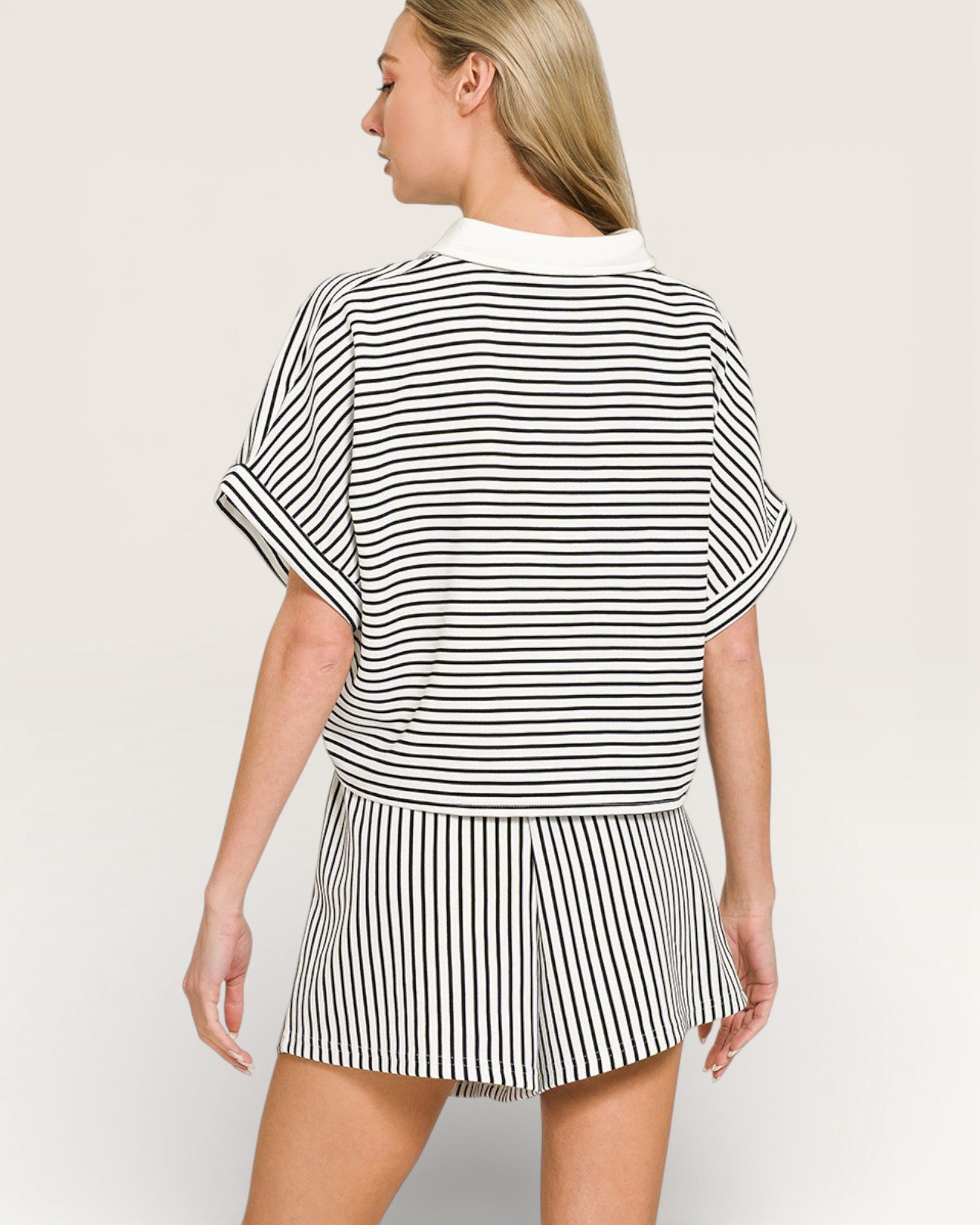 Woman wearing a black and white striped outfit on a plain background