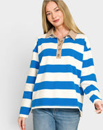 Woman wearing a blue and white striped shirt with a beige collar on a plain background