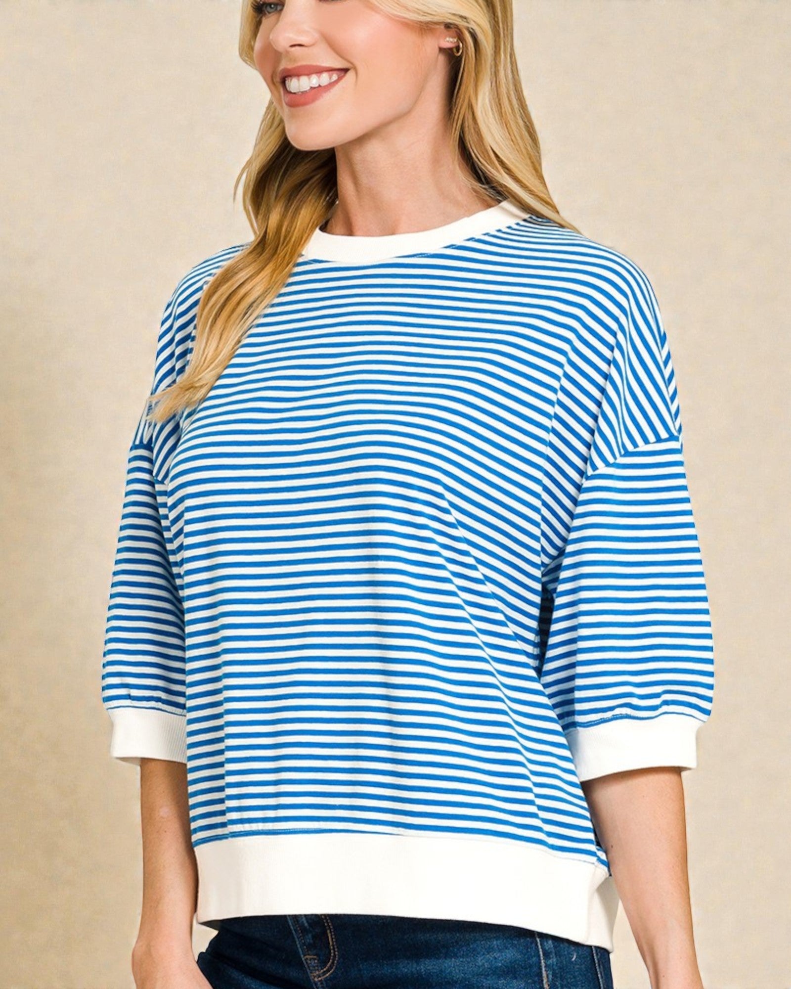 Woman wearing a blue and white striped sweater against a beige background