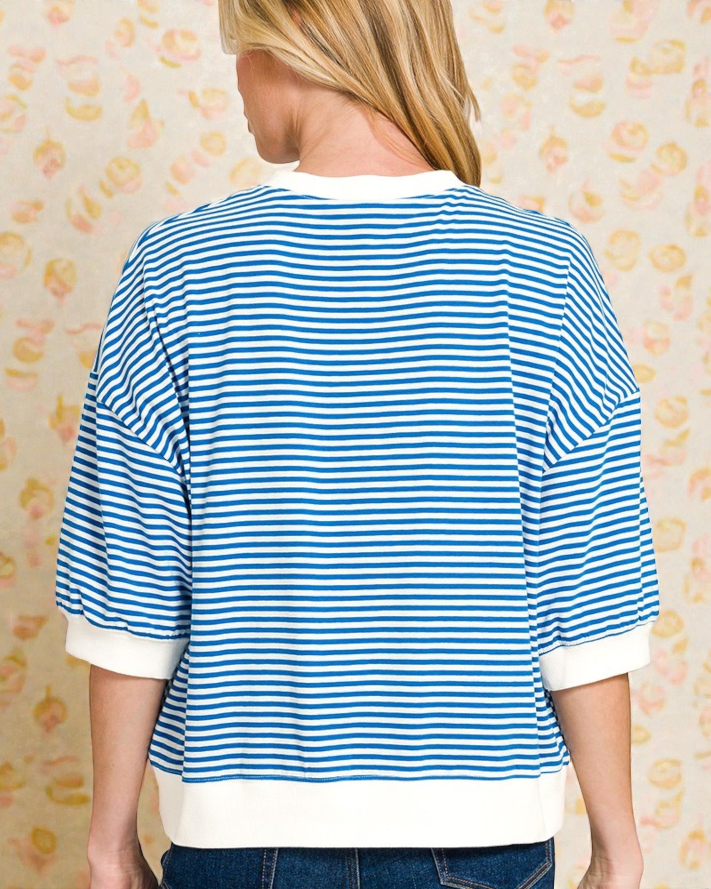 Person wearing a blue and white striped shirt with a patterned background