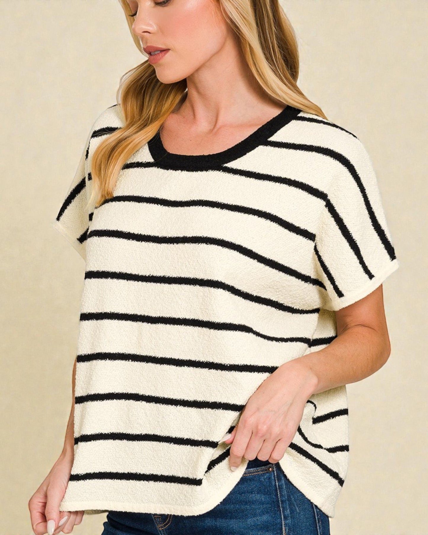 Woman wearing a black and white striped sweater against a beige background