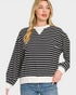 Woman wearing a black and white striped sweater with a plain background
