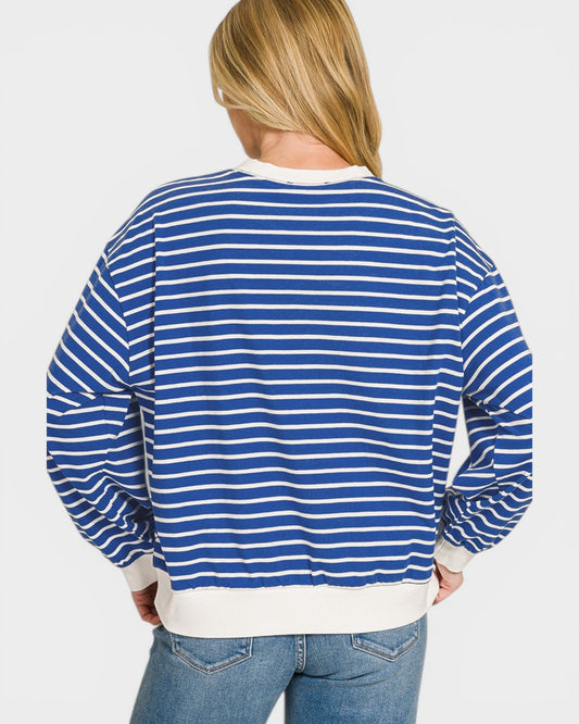 Person wearing a blue and white striped sweater on a plain background