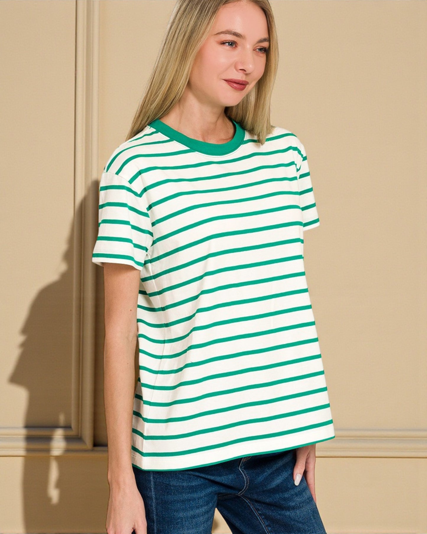 Woman wearing a green and white striped t-shirt against a beige wall.