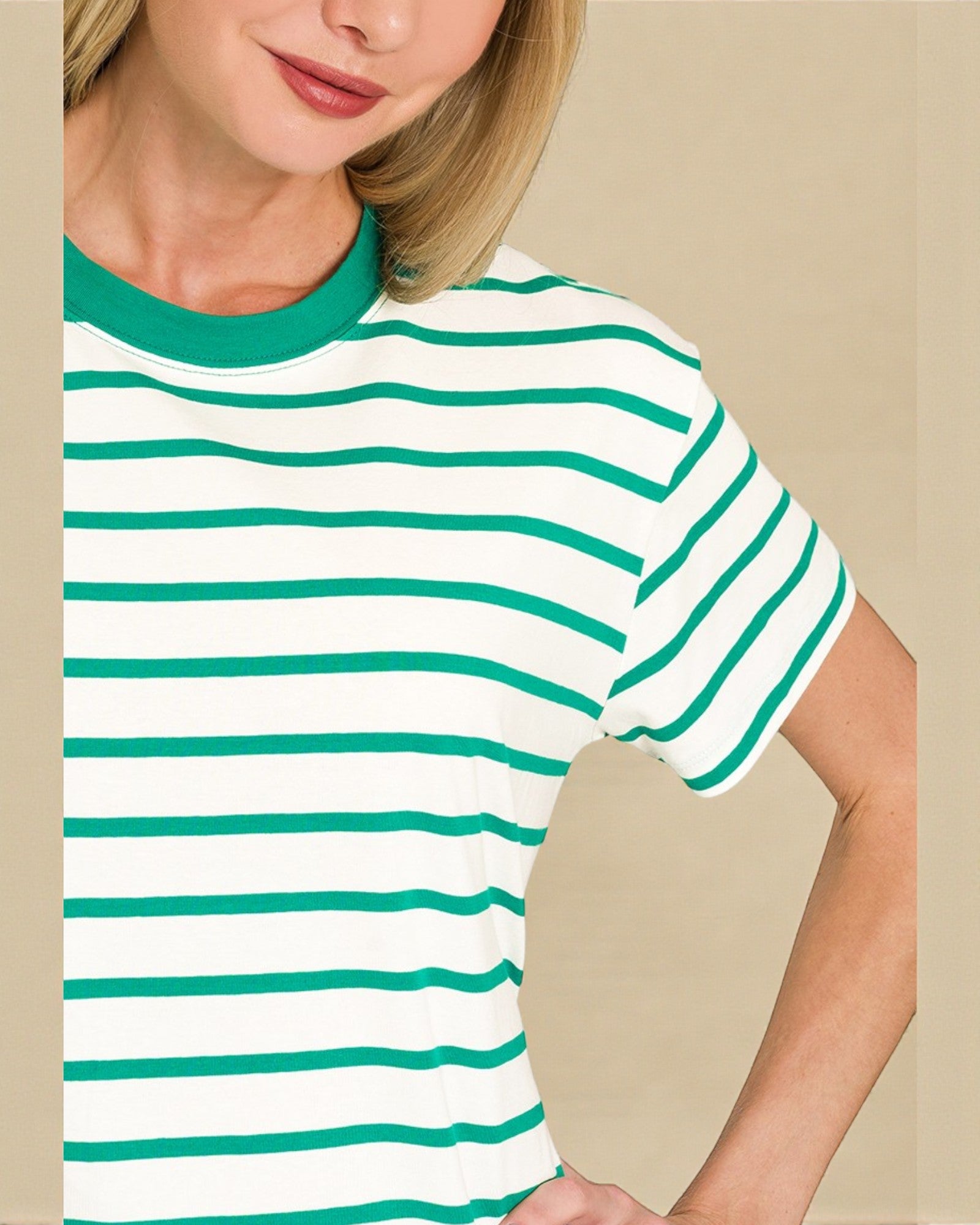 Person wearing a white t-shirt with green stripes against a beige background