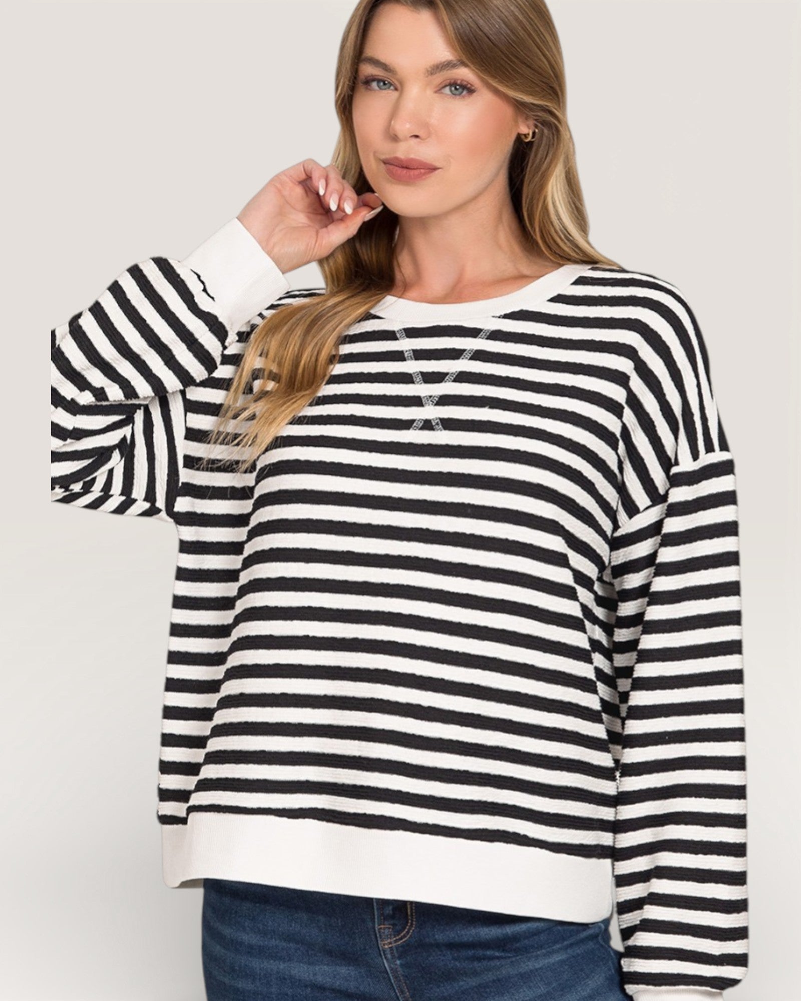 Woman wearing a black and white striped sweater on a plain background