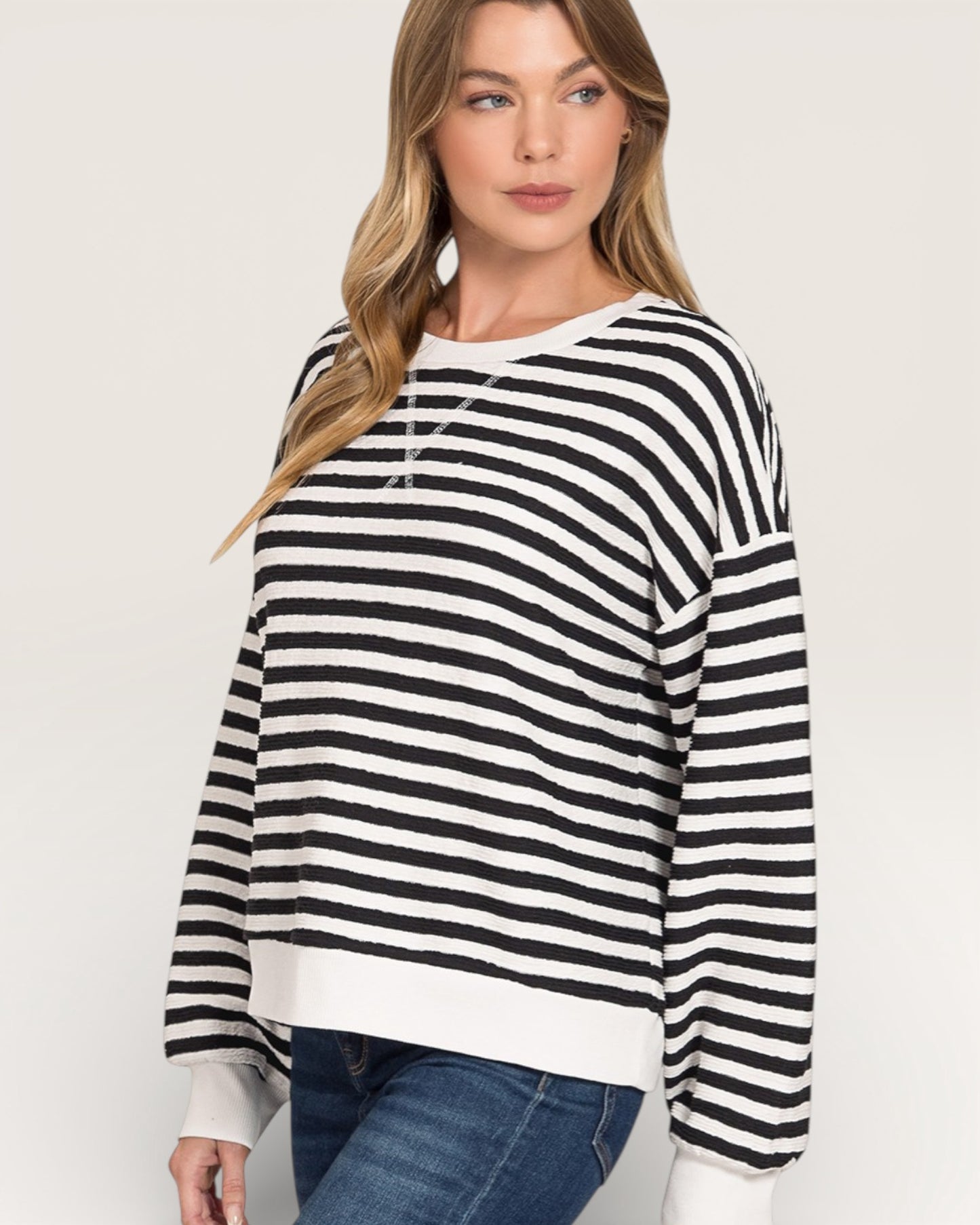 Woman wearing a black and white striped sweater on a plain background